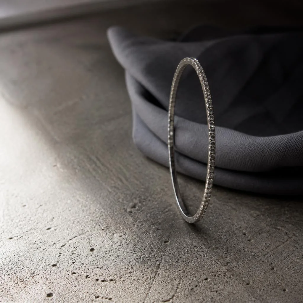 Thin white gold diamond bangle on concrete